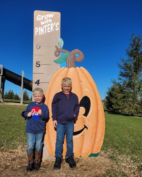 Two boys getting measured with Grow With Pinter's height measurement at Pinter's Pumpkin Patch