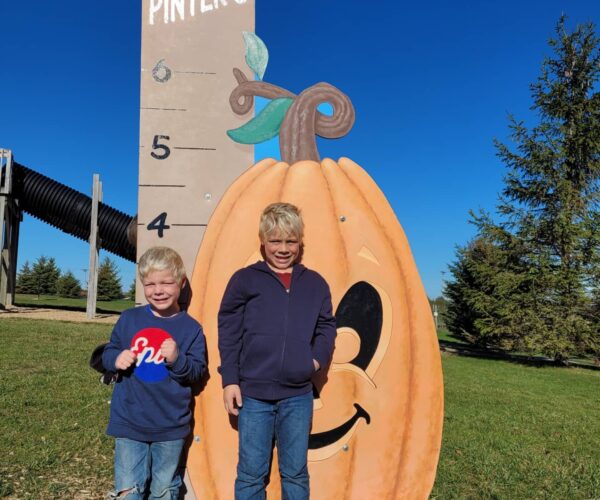 Two boys getting measured with Grow With Pinter's height measurement at Pinter's Pumpkin Patch